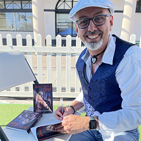 Mark Greenawalt book signing Blood From A Rose at the Mesa Book Festival with cover photo of Lindsey Lockwood